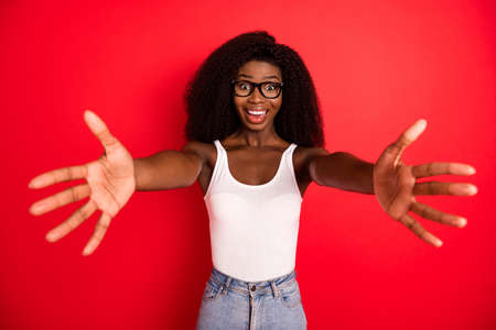 Photo of young attractive afro girl happy positive smile open arms hug cuddle friendly isolated over red color backgroundの写真素材