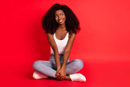 Portrait of attractive cheerful girl sitting in lotus pose thinking copy space isolated over bright red color backgroundの写真素材