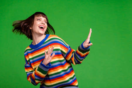 Photo of charming nice young happy dream funky woman look empty space dance isolated on green color backgroundの写真素材