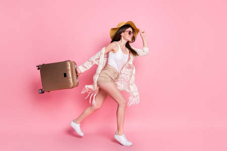 Photo of pretty sweet young lady wear lace cardigan cap smiling holding suitcase running isolated...