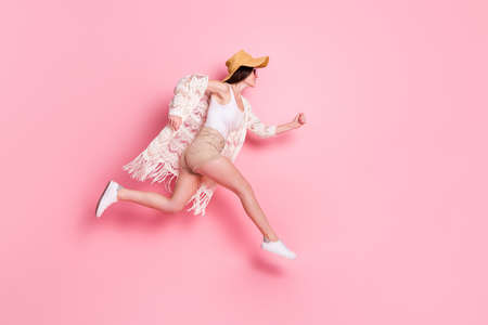 Photo of adorable cute young lady wear lace cardigan cap smiling jumping high hurrying isolated pink color backgroundの写真素材