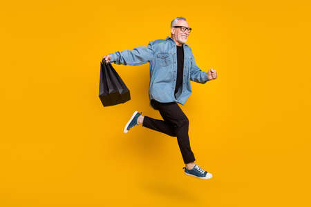 Full body profile photo of funny grandpa hold bags run wear jacket pants isolated on yellow color...