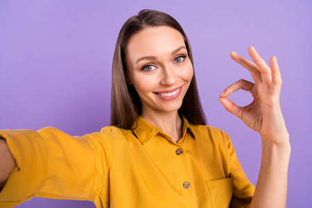 Photo portrait of smiling woman showing okay sign smiling isolated on pastel violet color background