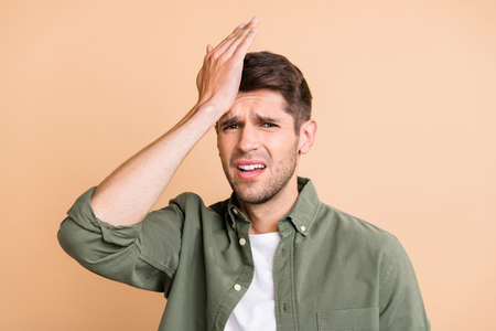 Photo of unhappy upset young man hold hand head ache pain suffer isolated on pastel beige color...