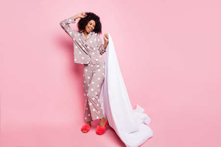 Photo of pretty charming wavy dark skin lady dotted sleepwear dancing holding white blanket isolated...