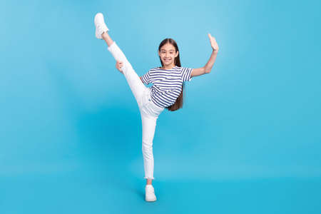 Full length body size careless small girl doing sport excercises smiling isolated pastel blue color...