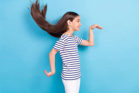 Profile side photo of young girl happy positive smile fooling playful dance look empty space isolated over blue color backgroundの写真素材