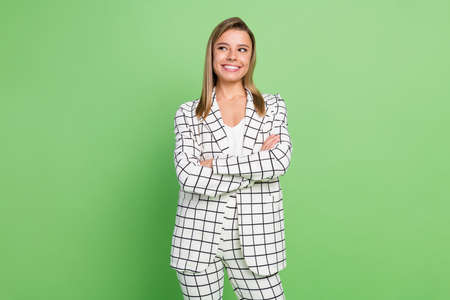 Portrait of attractive cheerful classy girl thinking copy empty space folded arms isolated over bright green color backgroundの写真素材