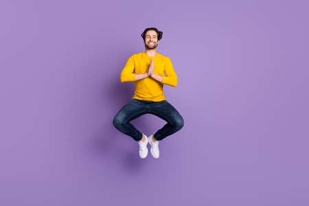 Full length body size photo smiling man in casual outfit jumping up practising yoga isolated pastel purple color backgroundの写真素材