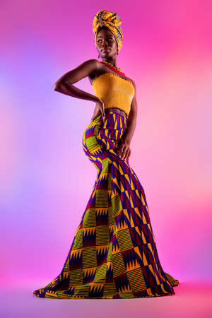 Full length photo of magnificent young dark skin woman look empty space vogue tribal dress isolated on neon backgroundの写真素材