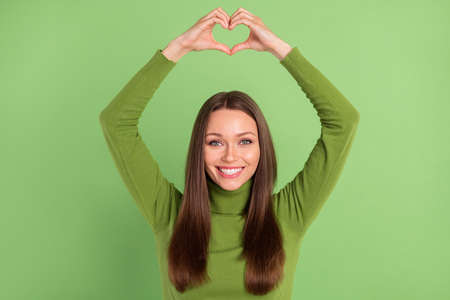 Photo portrait happy woman showing heart sign with fingers isolated pastel green color backgroundの写真素材