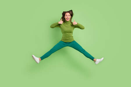 Full size photo of charming young happy lady jump up amazed make thumbs up isolated on green color backgroundの写真素材