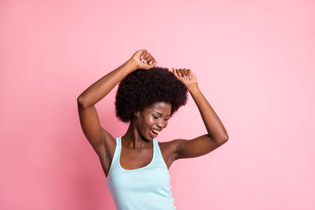 Portrait of optimistic brunette curly lady hands up dance wear blue top isolated on pink color...
