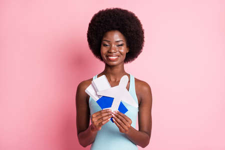 Portrait of optimistic nice brunette curly lady hold tickets plain wear blue top isolated on pink color backgroundの写真素材