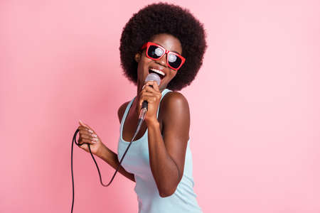 Photo of happy funky dark skin young woman hold sing mic music lover isolated on pink color...
