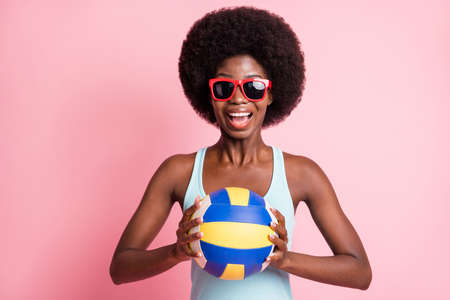 Portrait of optimistic nice brunette curly lady hold ball wear spectacles blue top isolated on pink color backgroundの写真素材