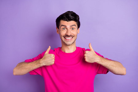 Photo of sweet funny young man wear pink t-shirt showing thumbs upの写真素材