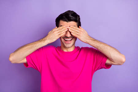 Photo of funny playful young man wear pink t-shirt arms cover eyesの写真素材