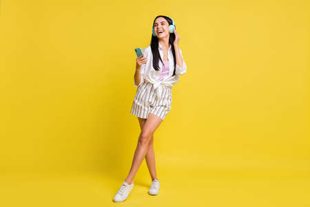 Full size photo of young charming pretty smiling girl use phone listen music in earphonesの写真素材