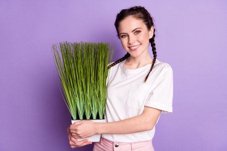 Photo of attractive happy nice young woman hold hands pot flower nature smile isolated on violet color backgroundの写真素材