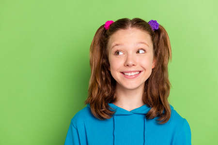 Photo of positive young happy little girl look empty space good mood smile isolated on green color backgroundの写真素材