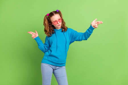 Photo of young serious charming cool girl look empty space point fingers gun isolated on green color backgroundの写真素材