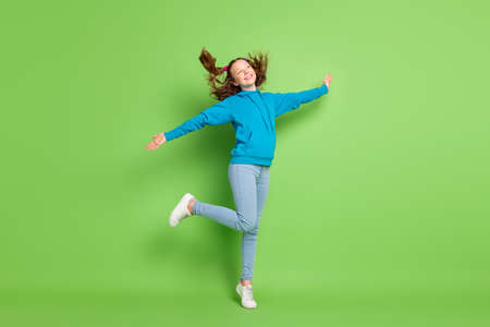 Full size photo of happy cheerful dreamy girl look empty space fly hair isolated on green color backgroundの写真素材