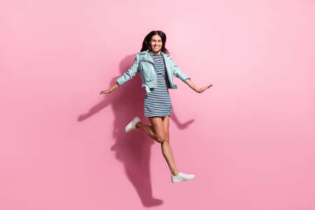 Full length photo of cute charming young girl dressed blue jacket jumping high isolated pink color...