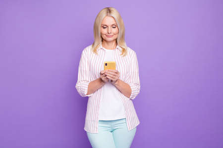 Photo of shiny adorable mature woman dressed pink shirt typing modern device isolated purple color...