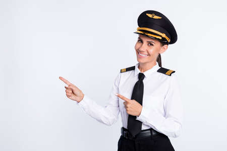 Photo of pretty positive lady direct finger empty space wear hat aviator uniform isolated white color backgroundの写真素材