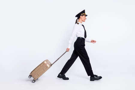 Profile photo of girl go carry suitcase look empty space wear aviator headwear uniform isolated white color backgroundの写真素材