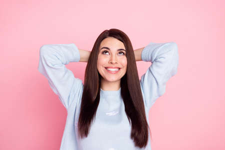 Portrait of adorable glad lady arms behind head look interested up empty space isolated on pink color backgroundの写真素材