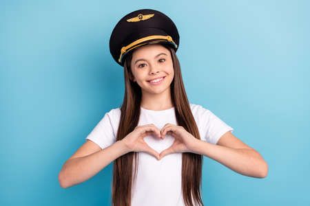 Portrait of attractive cheerful girl wearing hat showing heart sign symbol isolated over bright blue color backgroundの写真素材