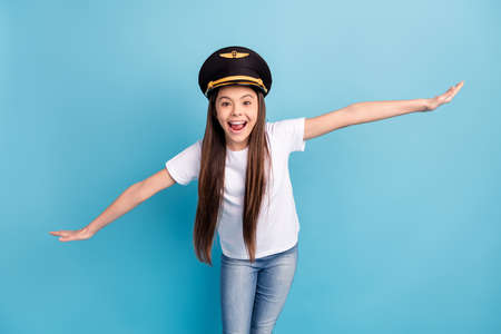 Portrait of attractive cheerful funny girl wearing hat having fun flying like plane isolated over...