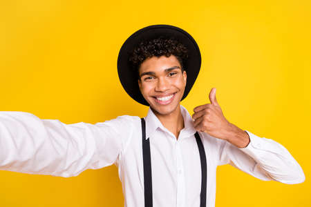Photo portrait of african american guy taking selfie showing thumb up isolated on vivid yellow colored backgroundの写真素材