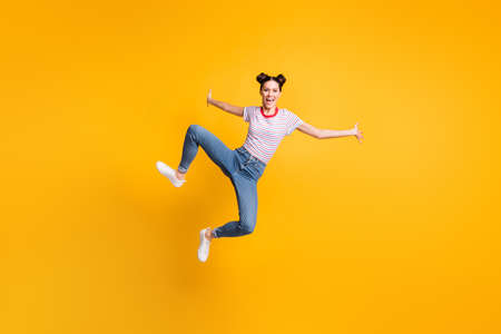 Full length photo of pretty adorable young girl dressed striped t-shirt jumping high isolated yellow...