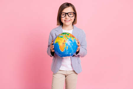 Portrait of attractive trendy cheerful girl holding in hands globe exploring map climate isolated over pink pastel color backgroundの写真素材