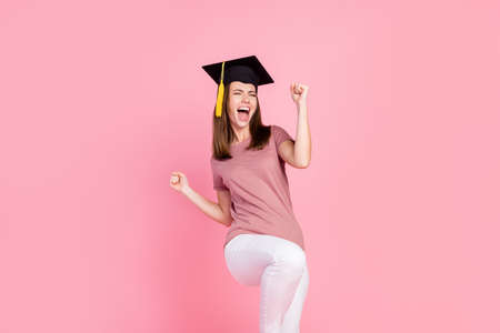 Portrait of attractive cheerful lucky girl graduating having fun isolated over pink pastel color backgroundの写真素材