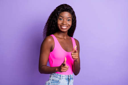 Photo of charming adorable dark skin woman dressed pink tank pointing fingers you isolated violet color backgroundの写真素材