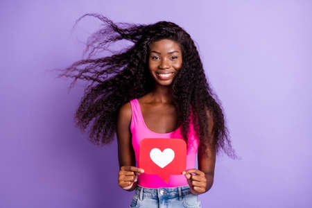 Photo of playful pretty dark skin lady wear pink singlet holding heart like card isolated purple color backgroundの写真素材