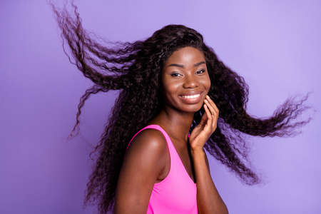 Photo portrait of african american girl with flying hair isolated on pastel pink colored backgroundの写真素材