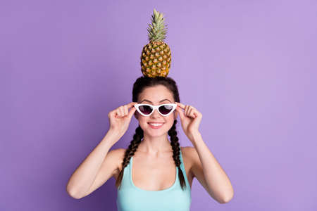 Photo of sweet funny brown hair lady hold pineapple wear spectacles blue top isolated on purple color backgroundの写真素材