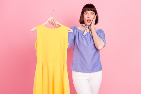 Photo portrait of pretty woman fitting clothes on shopping amazed high price isolated on pastel pink color backgroundの写真素材