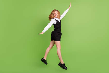Full length body size view of attractive cheerful girl jumping having fun isolated over bright green...