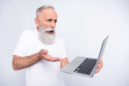 Portrait of attractive outraged worried man using laptop reading report isolated over light grey...
