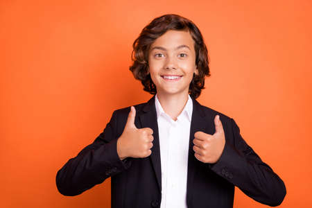 Photo of young charming attractive positive boy make thumbs up fingers recommend isolated on orange...
