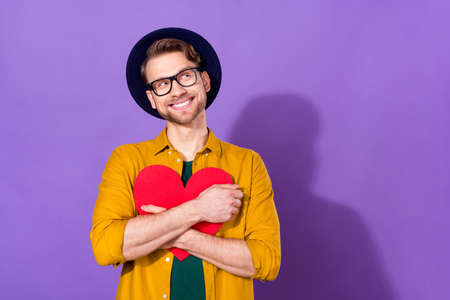 Photo of young man happy positive smile hug heart dream love feelings look empty space isolated over violet color backgroundの写真素材