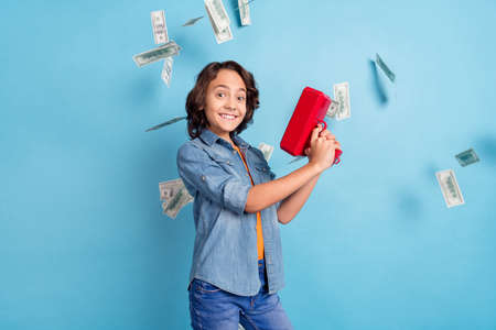 Profile side photo of young cheerful boy happy positive smile air fly cash money banknotes isolated over blue color backgroundの写真素材