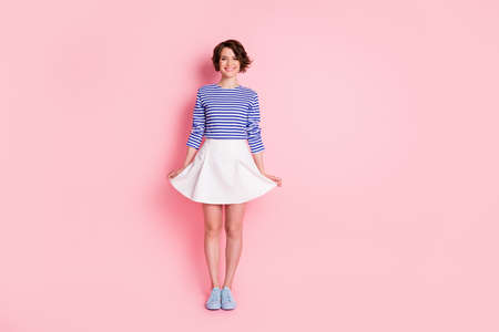 Full length photo of adorable girl toothy smile wear striped shirt mini skirt footwear isolated pastel pink color backgroundの写真素材