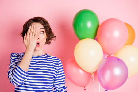 Portrait of young beautiful shocked amazed girl cover half face look copyspace hold balloons...